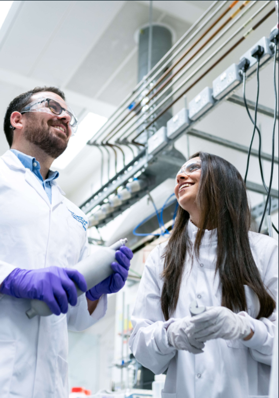 Two people wearing laboratory coat while standing in the laboratory
