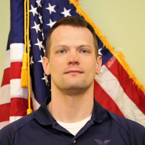 A man stands in front of the American flag